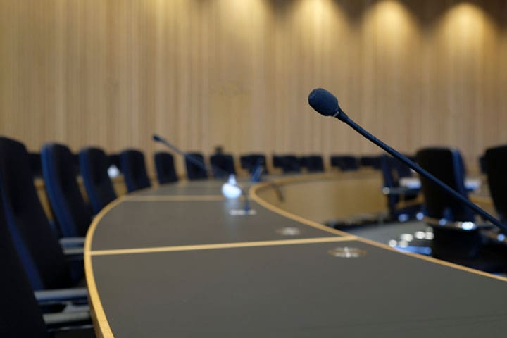 Konferenzraum mit Mikrofonen und Stühlen, bereit für eine Besprechung oder Präsentation